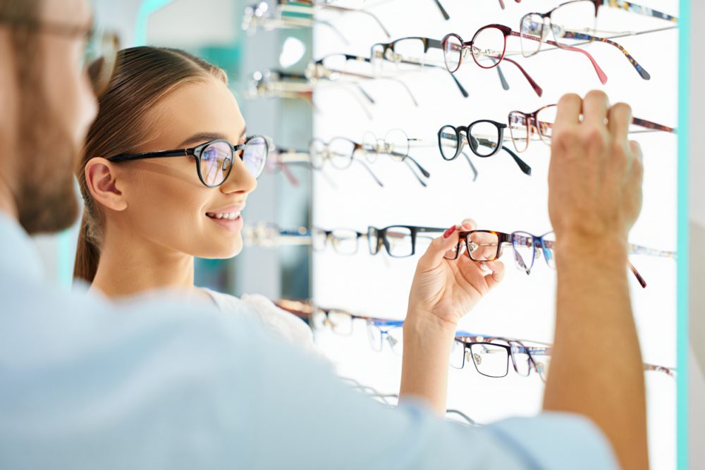 A customer choosing from a wall of stylish eyeglass frames at Beş Optik in Izmir