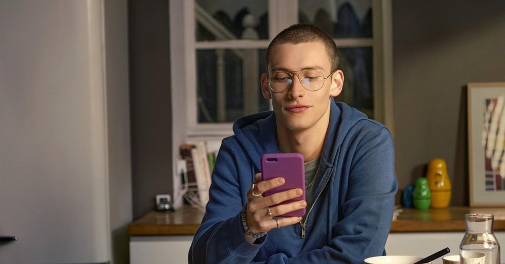 Evde mutfakta telefonuna bakan gözlüklü genç adam