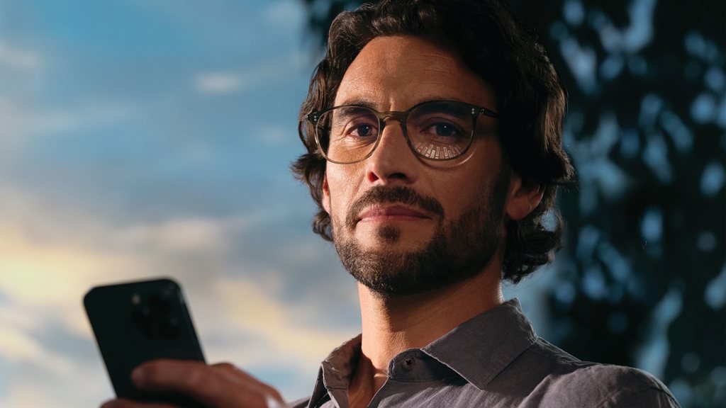 Elinde telefonla gökyüzüne bakan gözlüklü sakallı adam