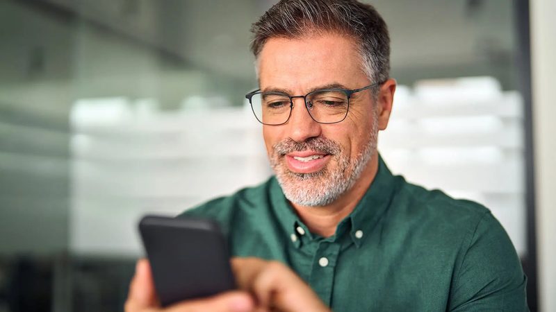 Telefonuna bakan gözlüklü adam