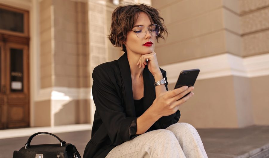 Sokakta yürürken telefonuna bakan gözlüklü kadın