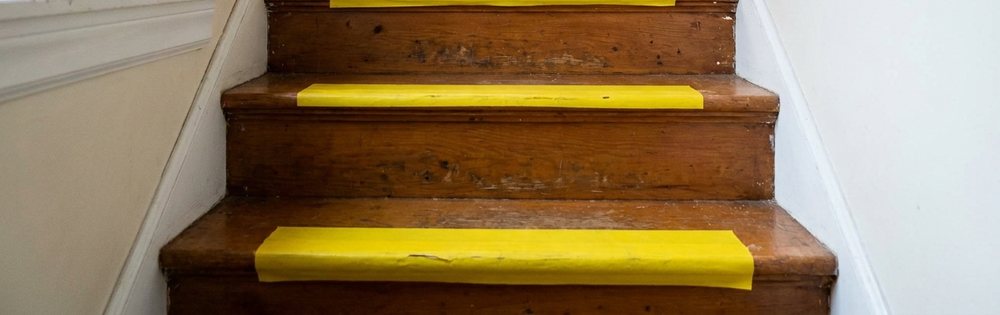 Basamak kenarları sarı bantla işaretlenmiş ahşap merdiven